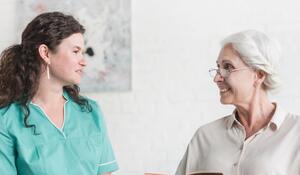 attractive-nurse-looking-senior-woman-patient-sitt
